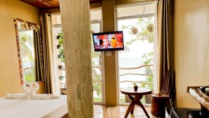 A hotel room with a bed, a TV, a view of the sea, a small table, and a piano. - Kaiyana Boracay Beach Resort (Boracay Island)