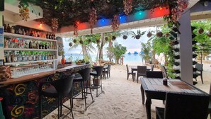 A beachside bar with a view of the sea, featuring a bar counter, seating area, and tropical decor. - Kaiyana Boracay Beach Resort (Boracay Island)
