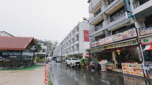 A street with a restaurant named Siam Thai, a coffee shop, and a building with balconies. - Royal Beach Residence (Patong)