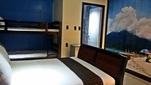 Una habitación de hotel con literas, una cama, un ventanal con vista a la playa y una puerta.