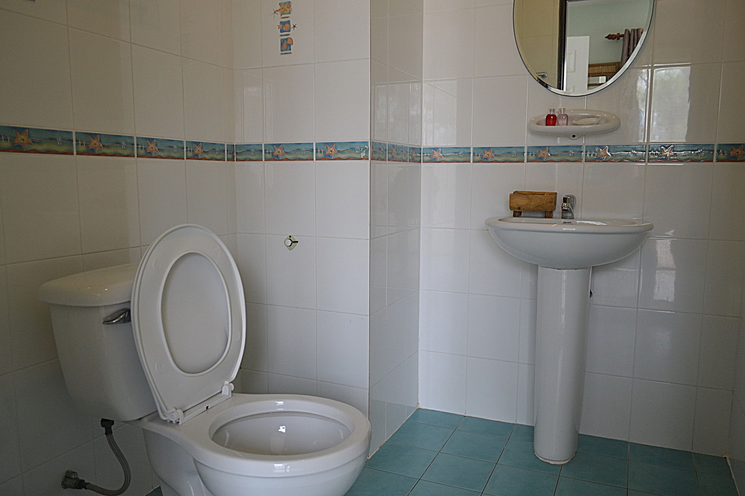 Ein Badezimmer mit Toilette, Waschbecken und Spiegel.