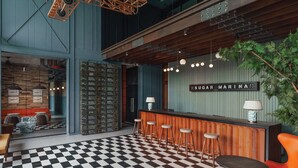 A bar area with a checkered floor, wooden bar counter, and stools. - Sugar Marina Hotel - AVIATOR - Phuket Airport (Sa Khu)