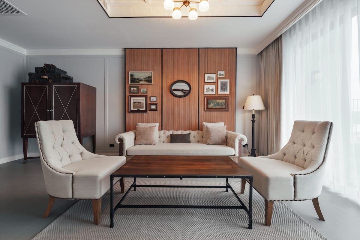 Una sala de estar moderna con un sofá, dos sillones, una mesita de centro y una pared decorada con cuadros.