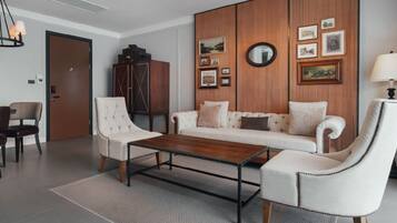 Una sala de estar moderna con un sofá, sillones, una mesa de centro, un mueble aparador y cuadros enmarcados en la pared.