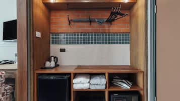 Una kitchenette compacta con protector contra salpicaduras de ladrillo, cafetera, tostadora y microondas.