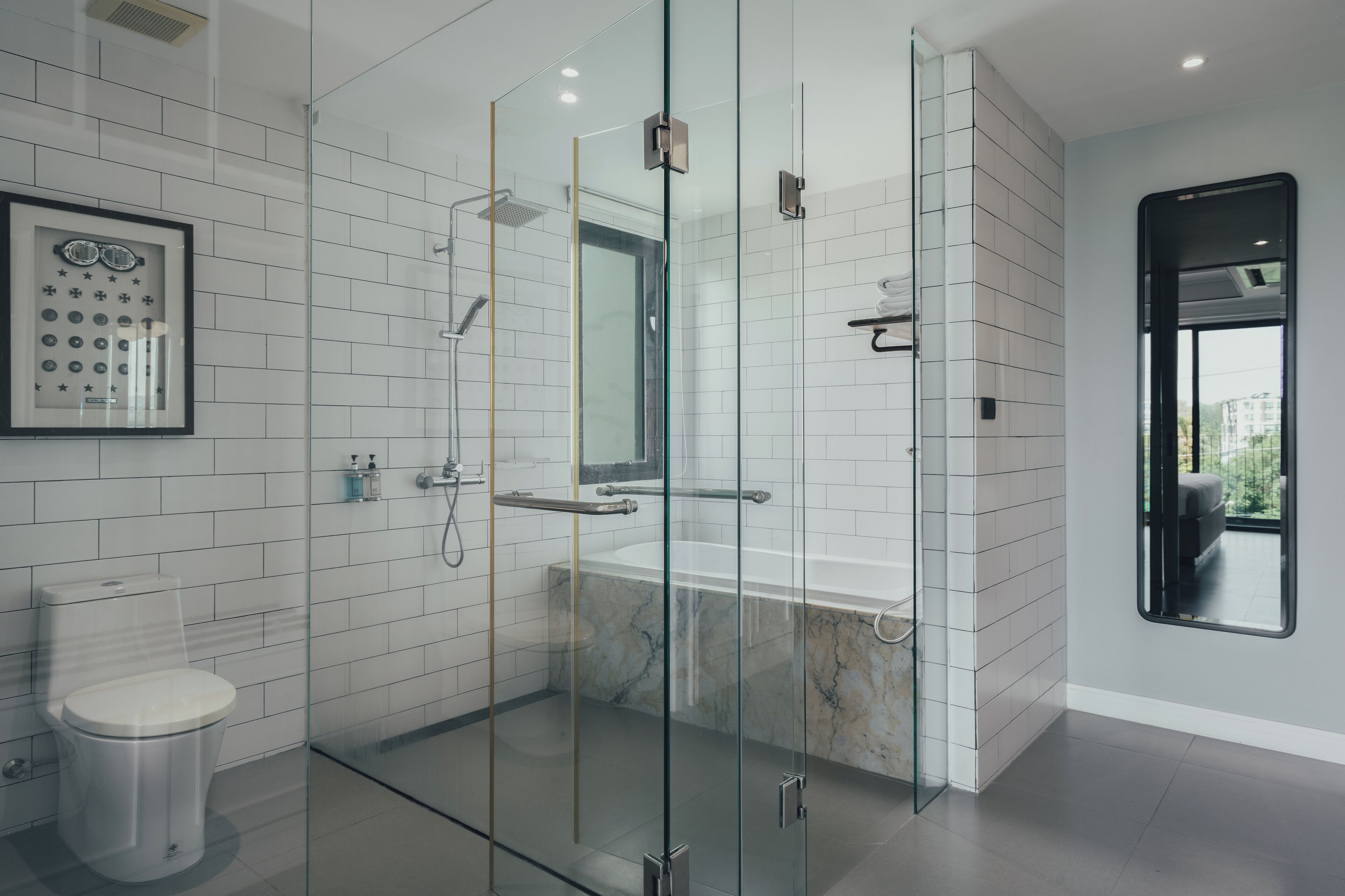 A modern bathroom with a glass-enclosed shower, a marble bathtub, and a toilet.