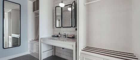 A modern bathroom with a white vanity, a large mirror, and a towel rack.