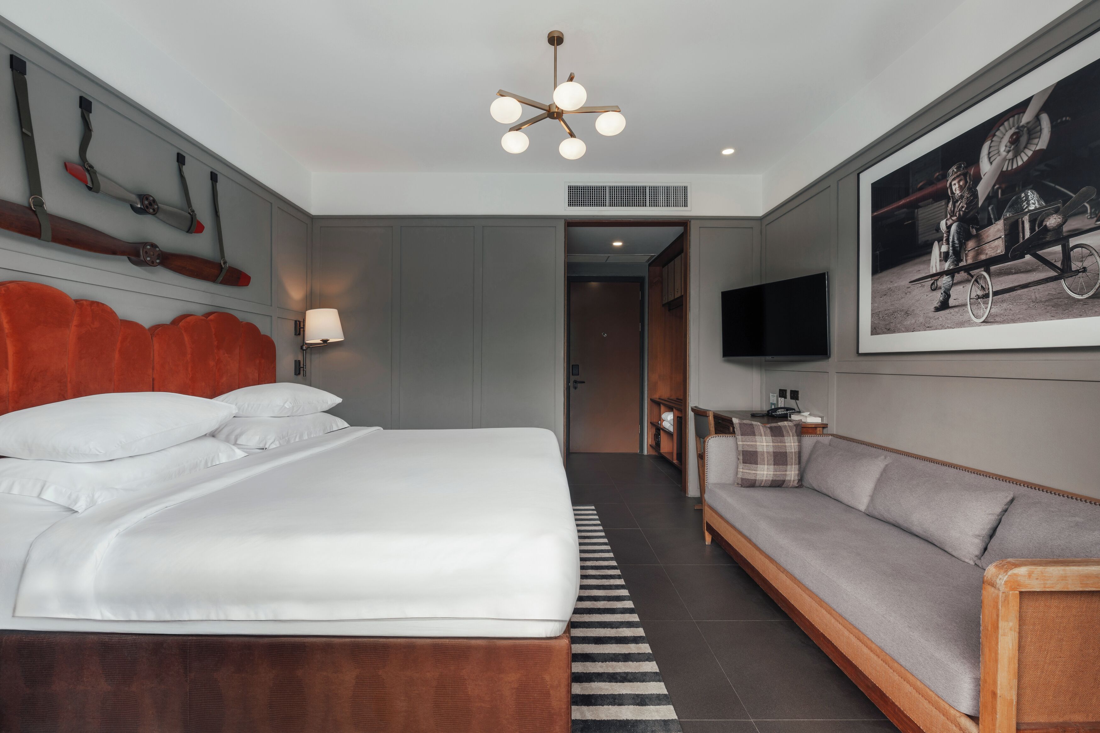Una habitación de hotel moderna con una cama grande, un sofá, un televisor y un cuadro en la pared.