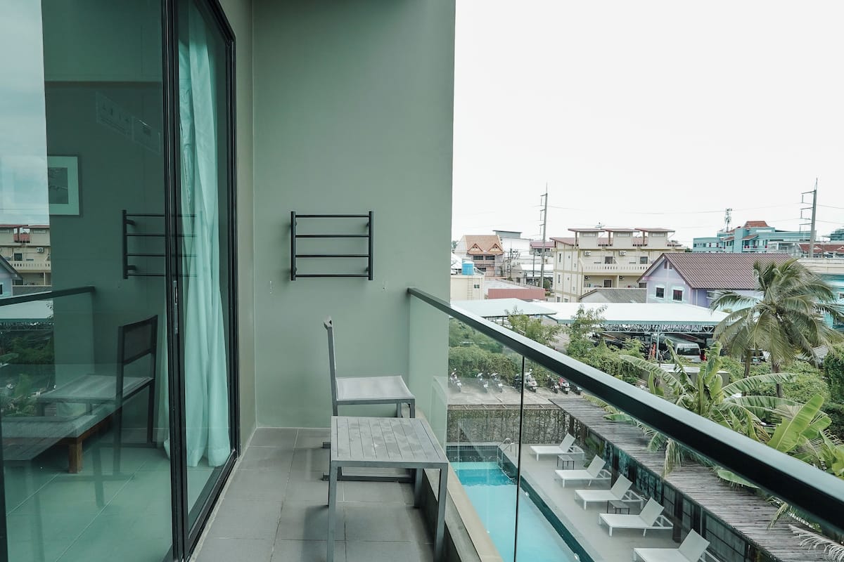 Un balcón con puerta de cristal, una mesa pequeña, un banco y vistas de la ciudad.