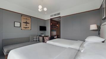 Una habitación de hotel con dos camas, televisión, armario de madera y lámpara en el techo.