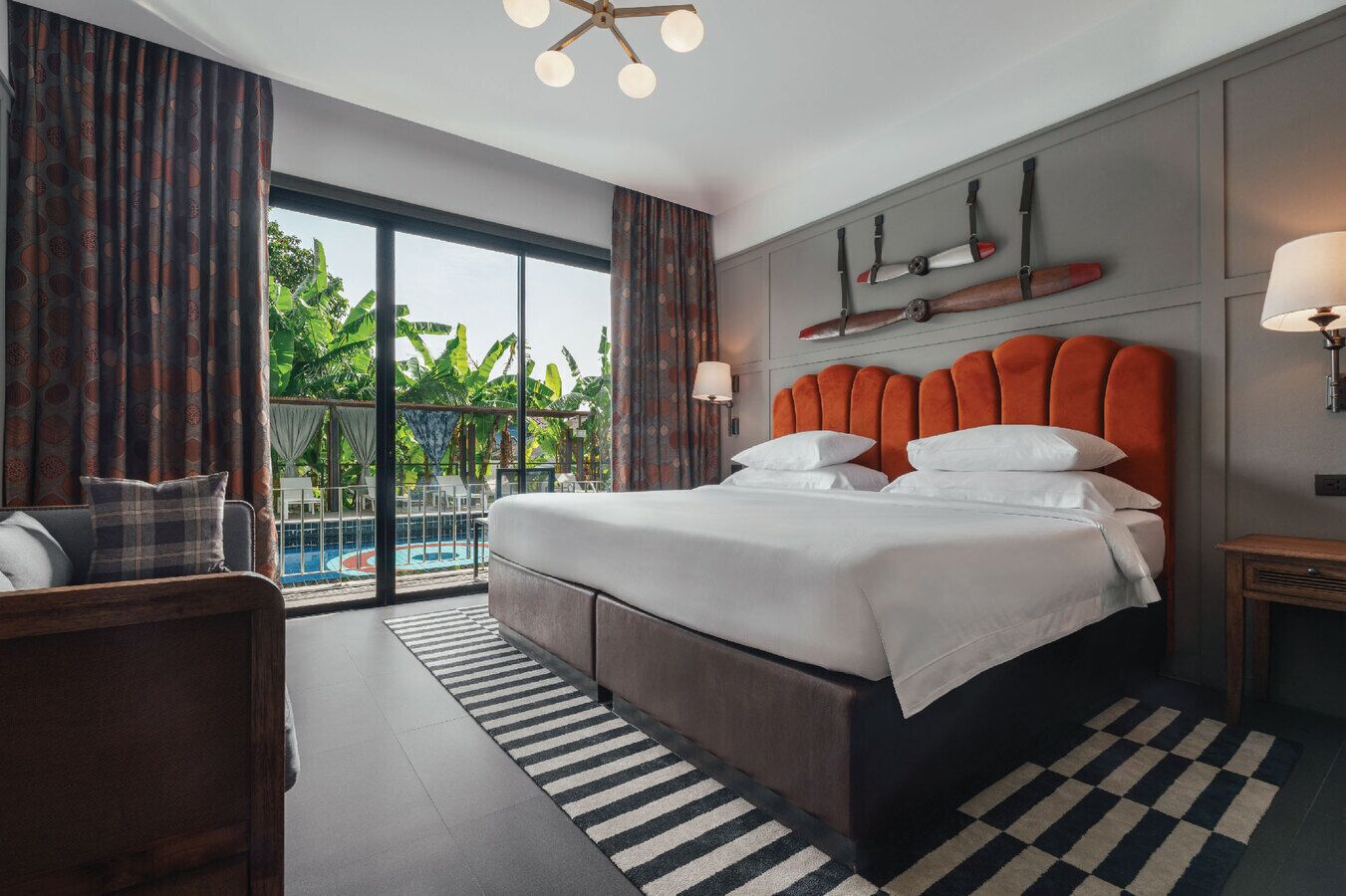 A hotel room with a large bed, a view of a pool, and a balcony.
