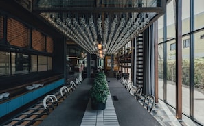 A modern interior with a long table, chairs, a potted plant, and a unique ceiling light fixture.