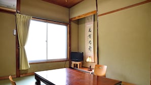 A traditional Japanese room with tatami flooring, a sliding door, a television, and a wooden table. - Yourou Onsen Honkan (Onomichi)