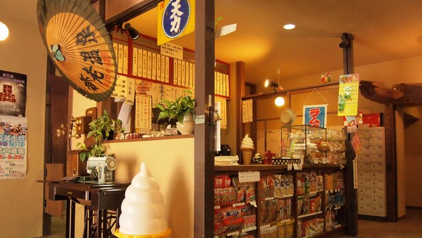 An interior with a traditional Japanese aesthetic, including a fan, a vending machine, and a display of snacks. - Yourou Onsen Honkan (Onomichi)
