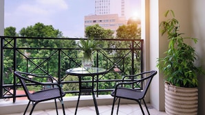 Ein Balkon mit zwei Korbstühlen, einem Glastisch und einem Blumentopf.