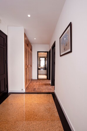 Un pasillo con piso de madera, un cuadro enmarcado en la pared y una puerta que da a un baño.