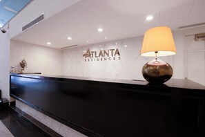Un mostrador de recepción con una pared de mármol, una lámpara y un cartel de Atlanta Residences.
