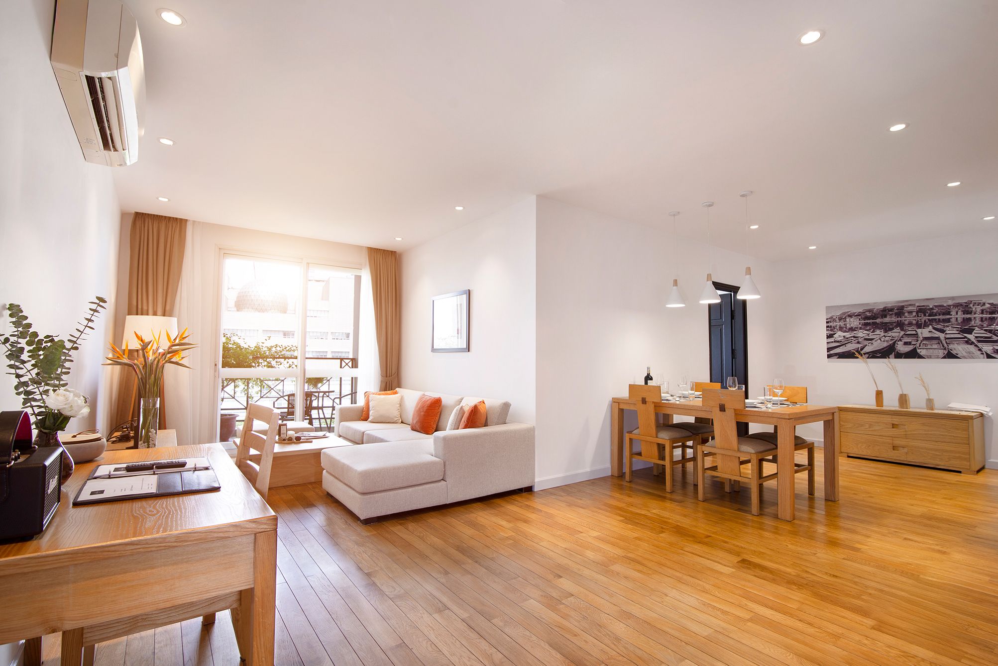 Un salon moderne avec un canapé, une table à manger et des chaises. Il y a une fenêtre avec des rideaux, une lampe et un tableau au mur.