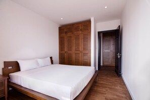 Un dormitorio con estructura de cama de madera, un armario de madera y una puerta que da a otra habitación.