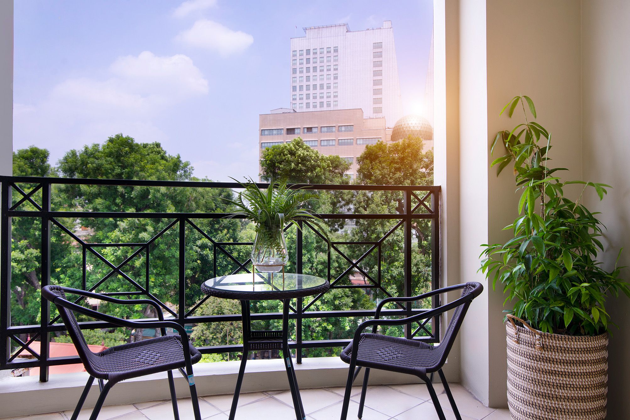 A balcony with a table and chairs, a potted plant, and a view of a building.