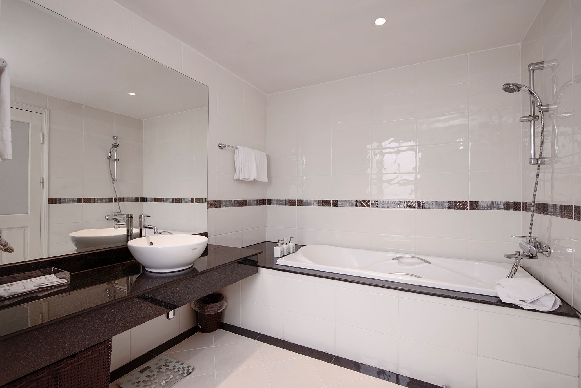 A modern bathroom with a large mirror, a sink, a bathtub, and a shower.