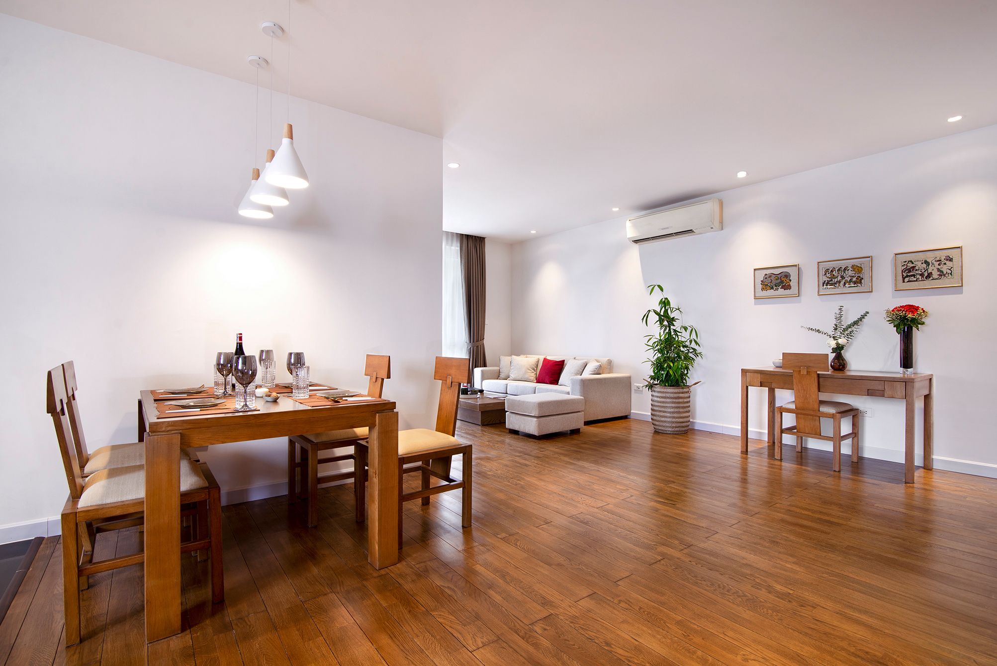 Un espai de vida modern amb zona de menjador, sofà, taula de centre i una planta.