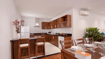 Una cocina moderna con armarios de madera, un comedor con una mesa lista para cuatro personas y un horno empotrado.