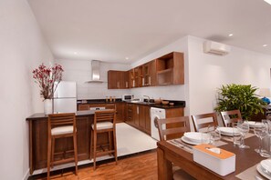 A modern kitchen with wooden cabinets, a dining area with a table set for four, and a built-in oven.