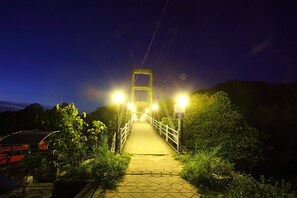 A nighttime pedestrian bridge with overhead lighting, surrounded by greenery. - PP Red Tuna Hut (Ko Phi Phi)
