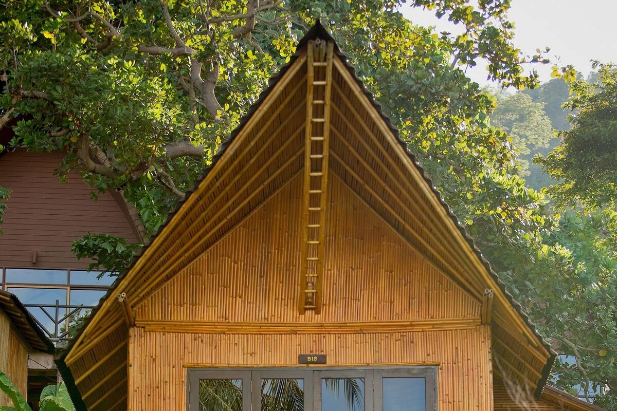 Eine Holzhütte mit einem Balkon, umgeben von üppiger Vegetation.