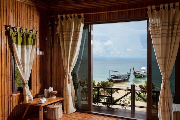 A wooden room with a large sliding glass door leading to a beach view.