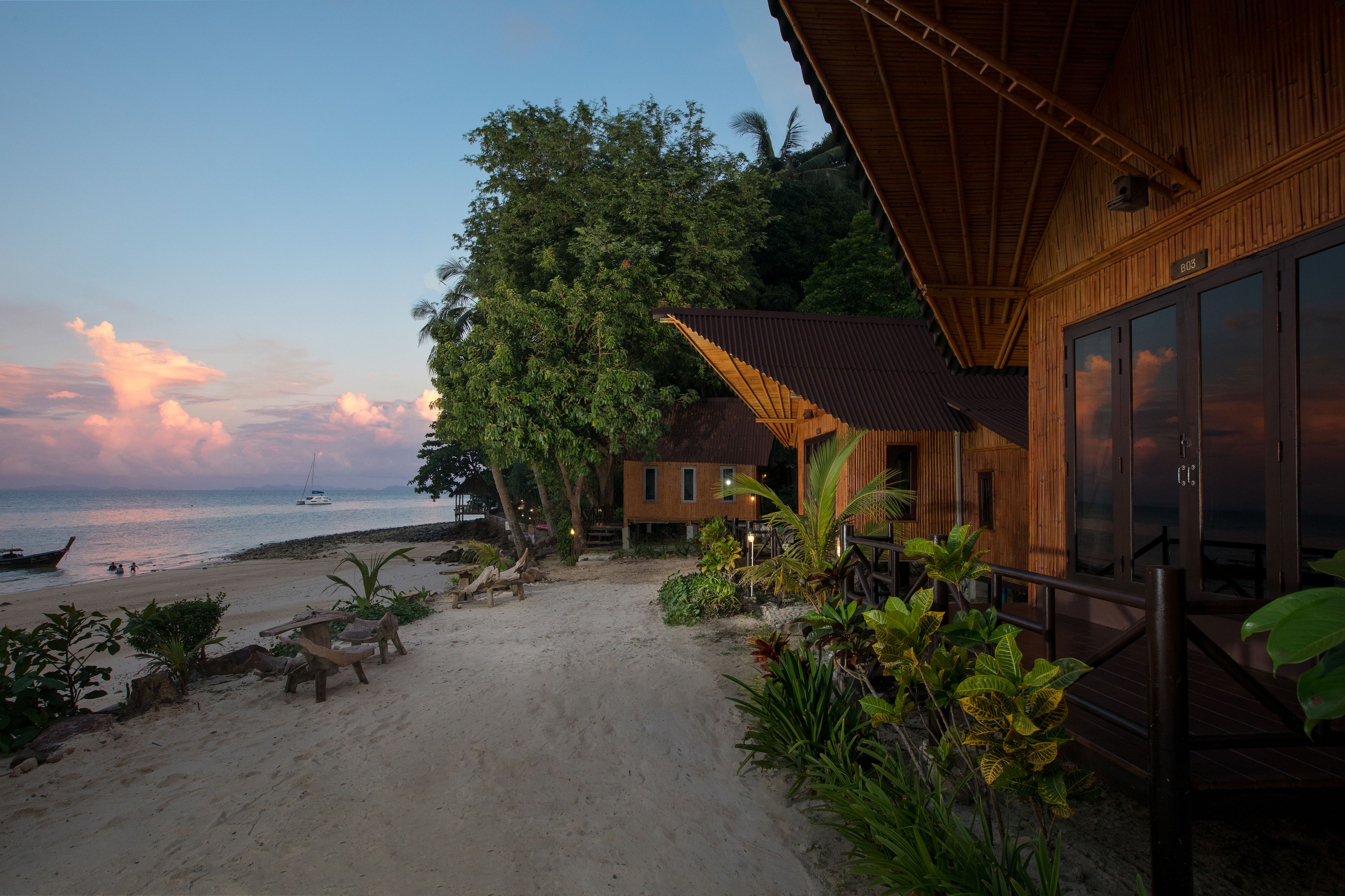 A wooden building with large windows, a beach view, and a sign reading "B03".