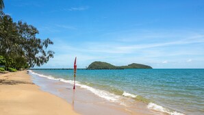 Una playa con agua azul cristalina, una orilla arenosa y un letrero que indica que no se permite bañarse.