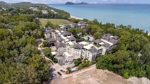 Vista aérea de un resort con varias construcciones, una playa y una vista despejada del océano.