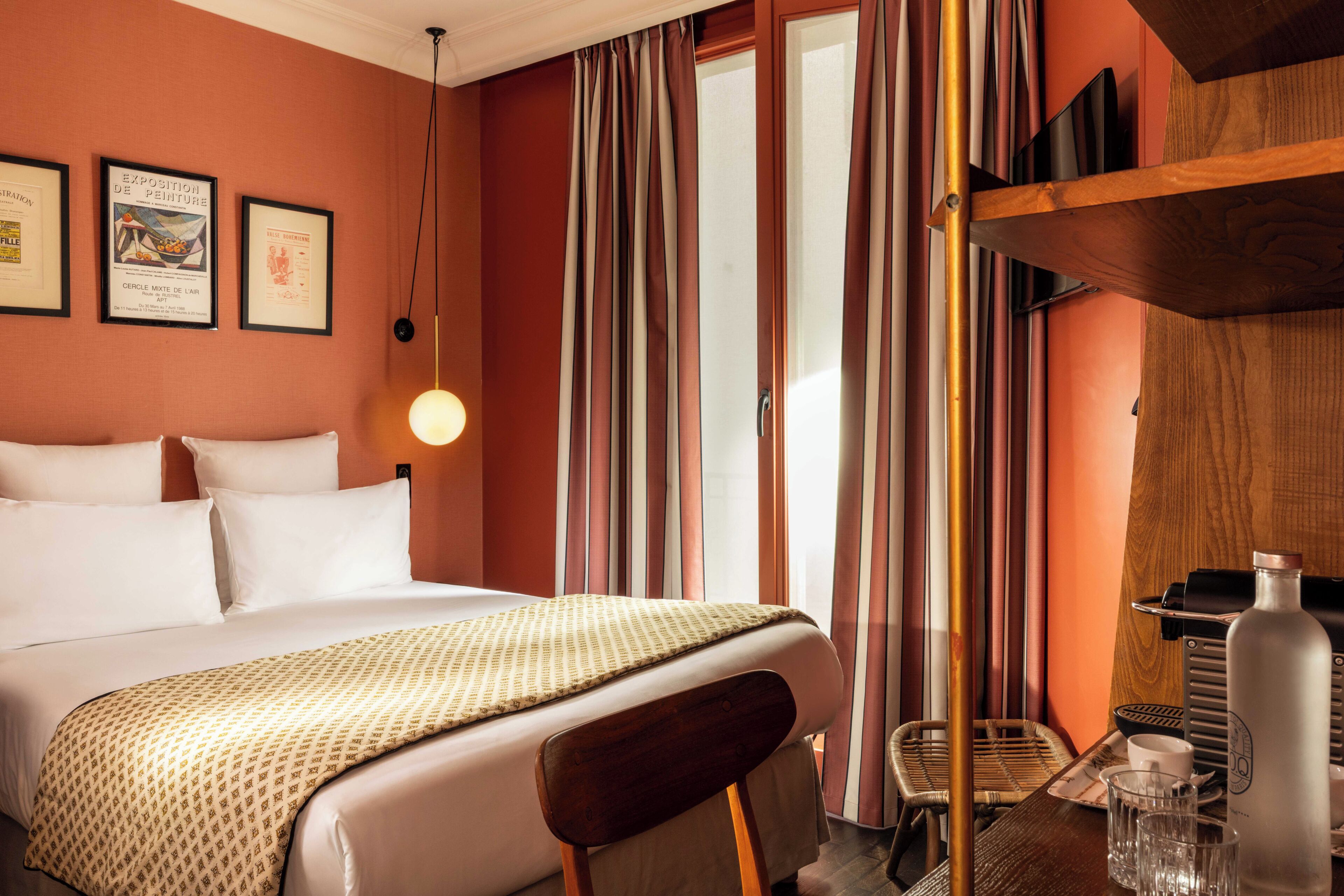 Ein Hotelzimmer mit einem Bett, einem Sessel, einem Tisch mit Wasserkocher und Vorhängen.