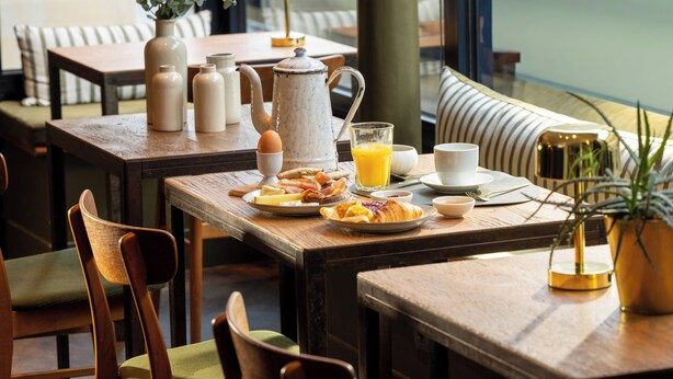 A breakfast setting with a table, chairs, and a view of the outdoors. - COQ Hotel Paris (Paris)