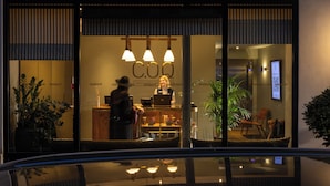 A modern hotel entrance with a reception desk, a sign reading 'COQ,' and a glass barrier. - COQ Hotel Paris (Paris)