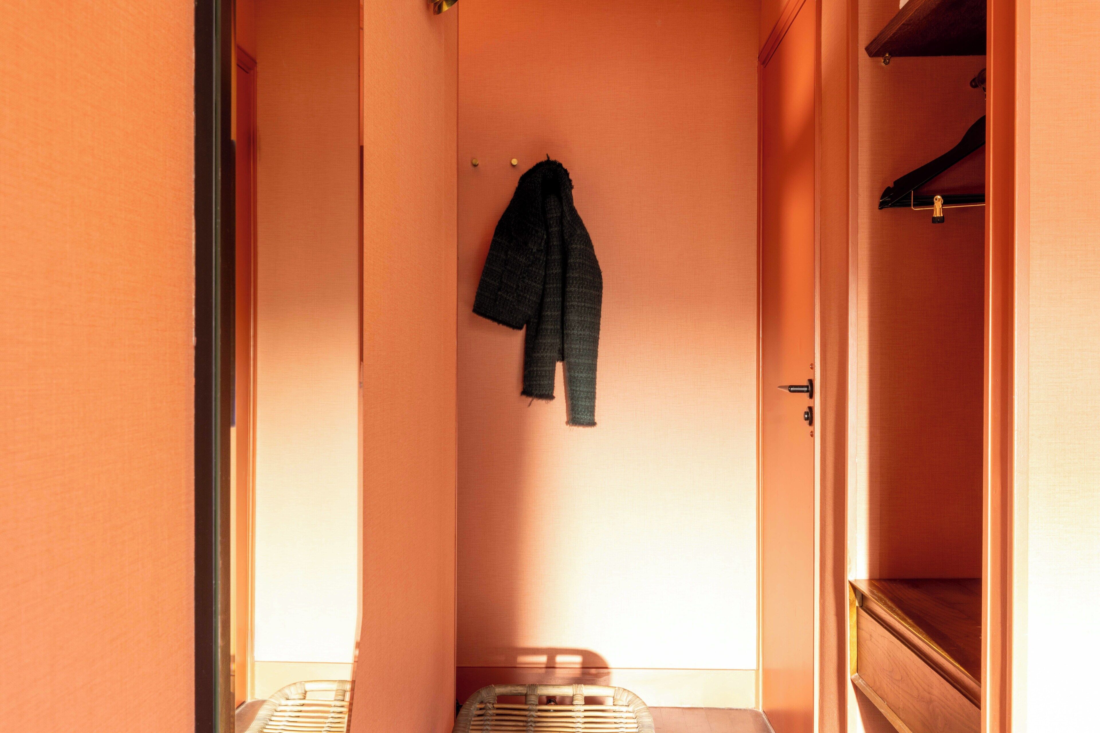 Ein schmaler Flur mit einem Kleiderhaken und einer Tür zu einem Zimmer.