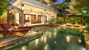 Een modern resort met een zwembad, ligbedden en een overdekt terras.