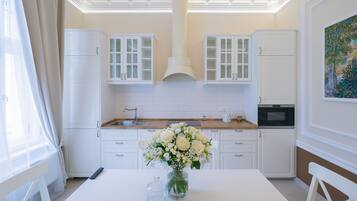 A modern kitchen with white cabinetry, a central island with a vase of flowers, and a microwave.