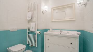 Un baño con inodoro, lavabo y toallero.