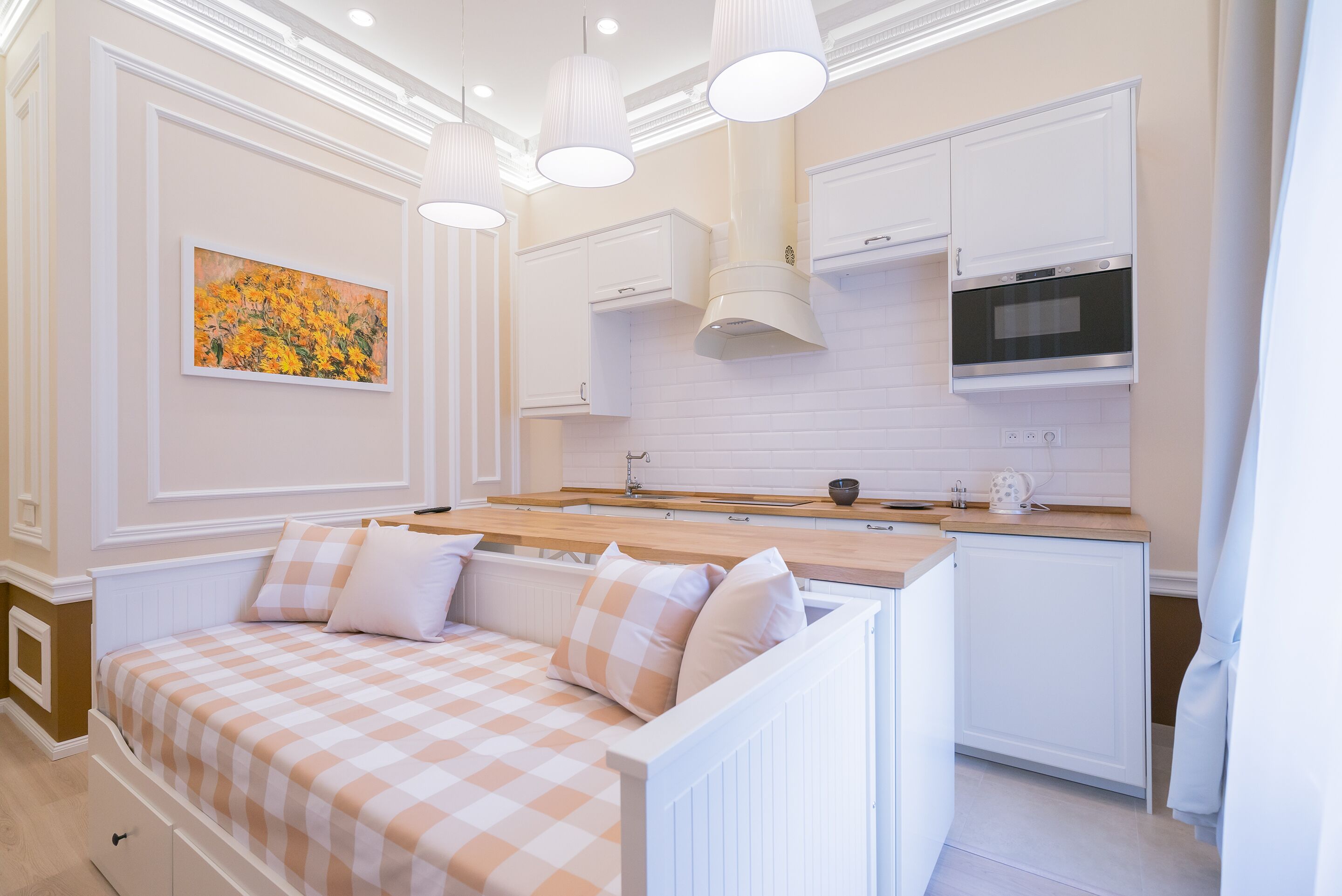 Una cocina moderna con armarios blancos, horno empotrado e iluminación colgante.