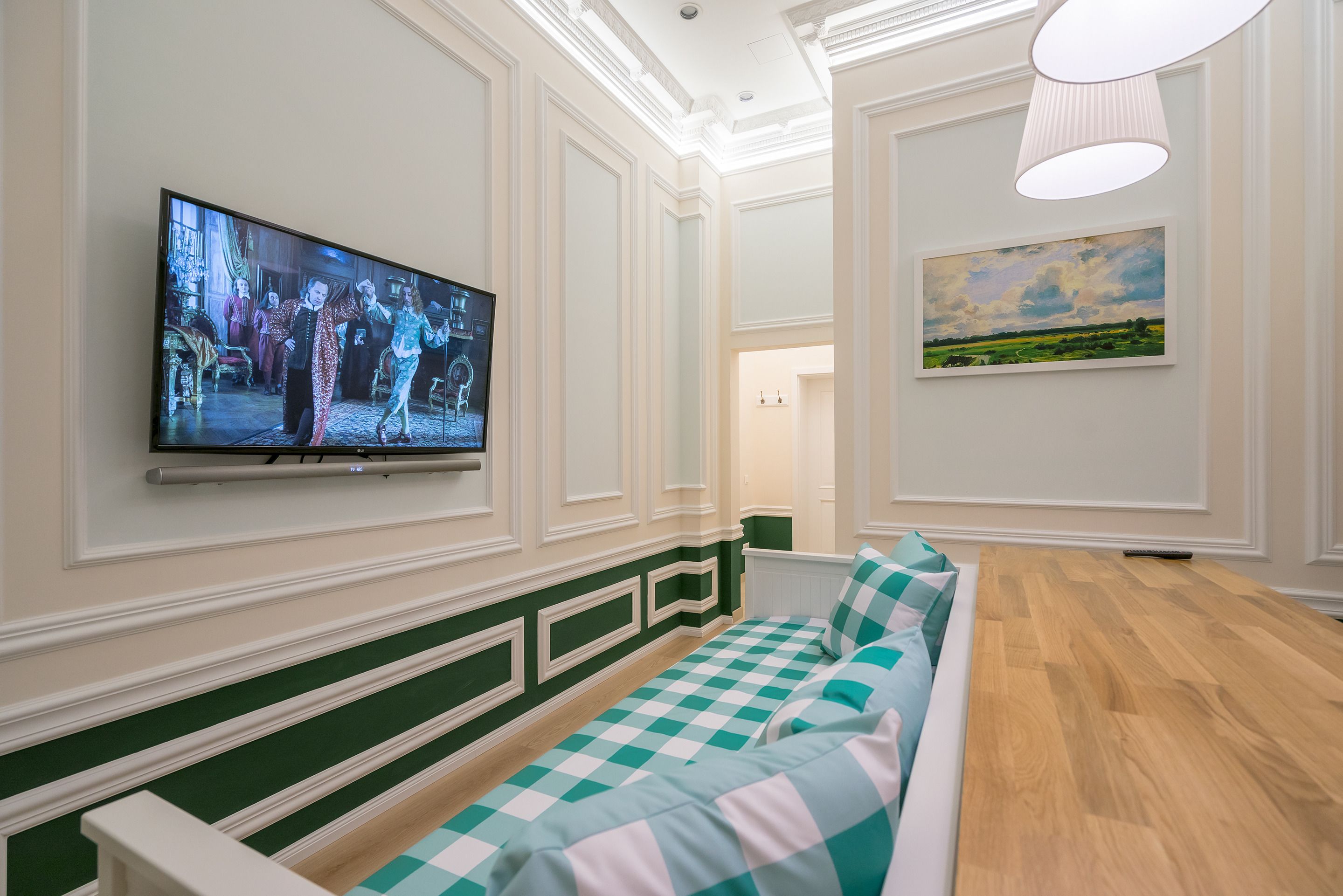 Un salon moderne avec un grand téléviseur à écran plat fixé au mur, un canapé à carreaux et un tableau accroché au mur.