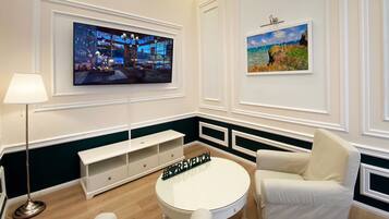 Un salon moderne avec un téléviseur à écran plat, une table basse ronde et deux fauteuils blancs.