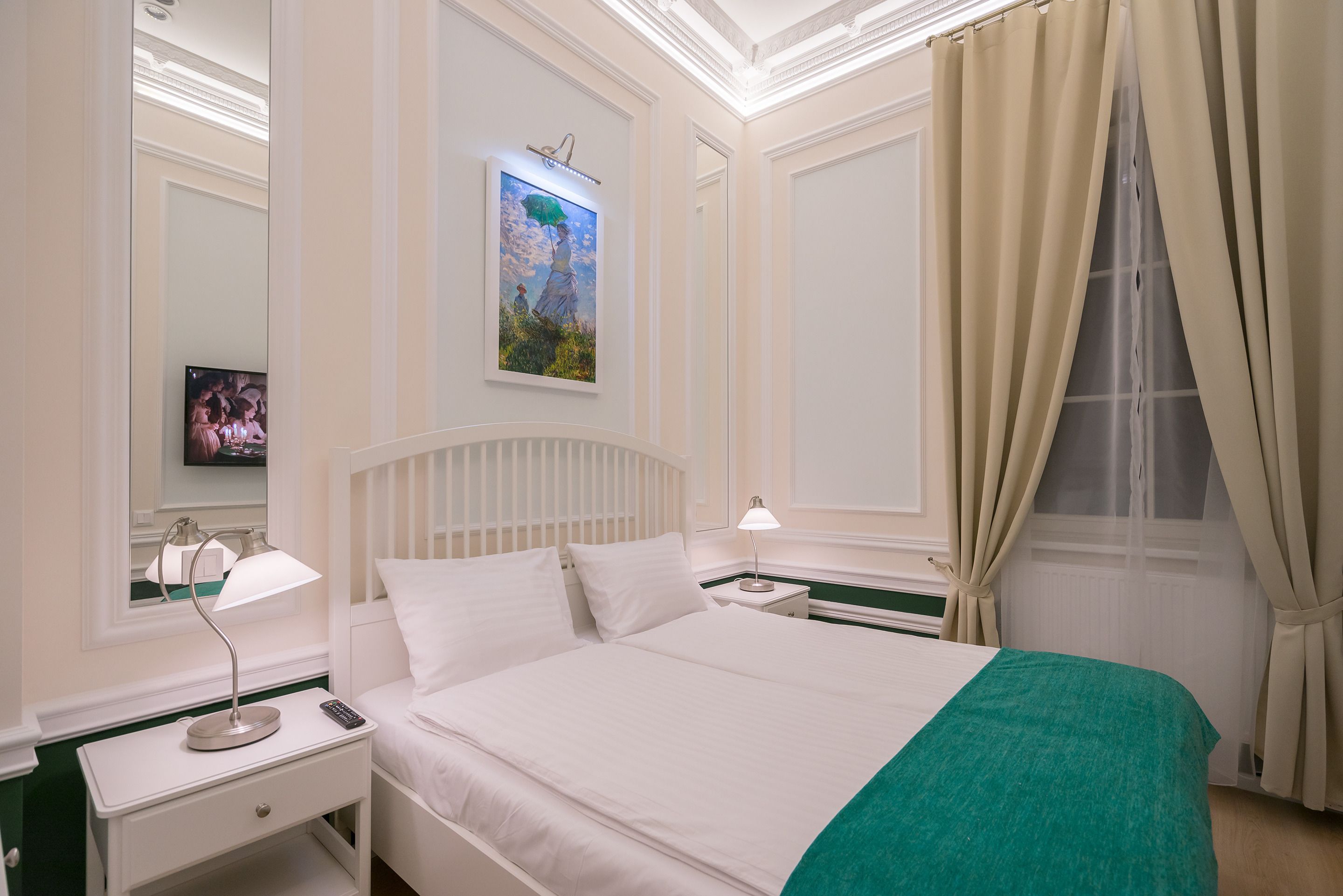 Una habitación de hotel con una cama, dos mesitas de noche, una lámpara, un cuadro, un televisor y una ventana con cortinas.