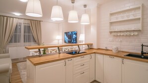 A modern kitchen with white cabinetry, a wooden countertop, and pendant lighting.