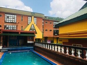 A pool area with a brick building in the background, a yellow awning, and a blue pool. - Divine Fountain Ajao (Lagos)