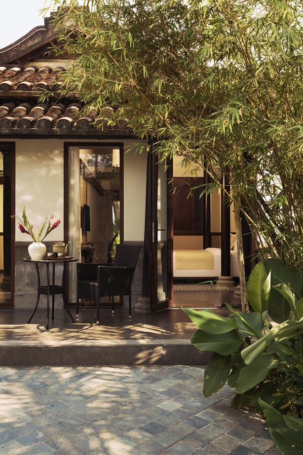 A traditional-style building with a tiled roof, a small table with a vase, and a chair.