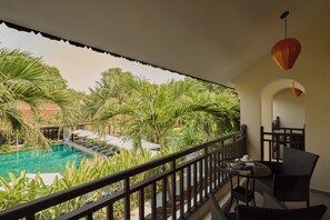 A balcony with a pool, outdoor furniture, and a view of a tropical garden. - Grand Signature Resort Hoi An by M Village, a brand of Modern Village Lifestyle (Da Nang)