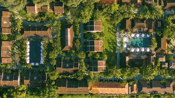 An aerial view of a resort with multiple bungalow-style accommodations, a central swimming pool, and lush greenery. - Grand Signature Resort Hoi An by M Village, a brand of Modern Village Lifestyle (Da Nang)